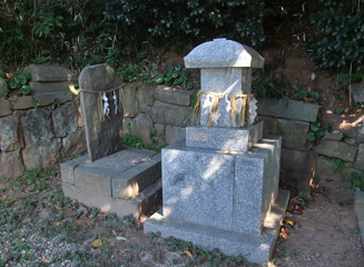 新しい祠の裏には古い石板が立っている